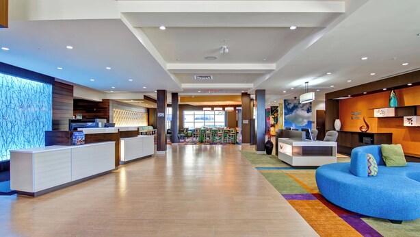 A modern hotel lobby with a reception desk, seating area, and a colorful rug. - Fairfield Inn and Suites by Marriott Kamloops (Kamloops)