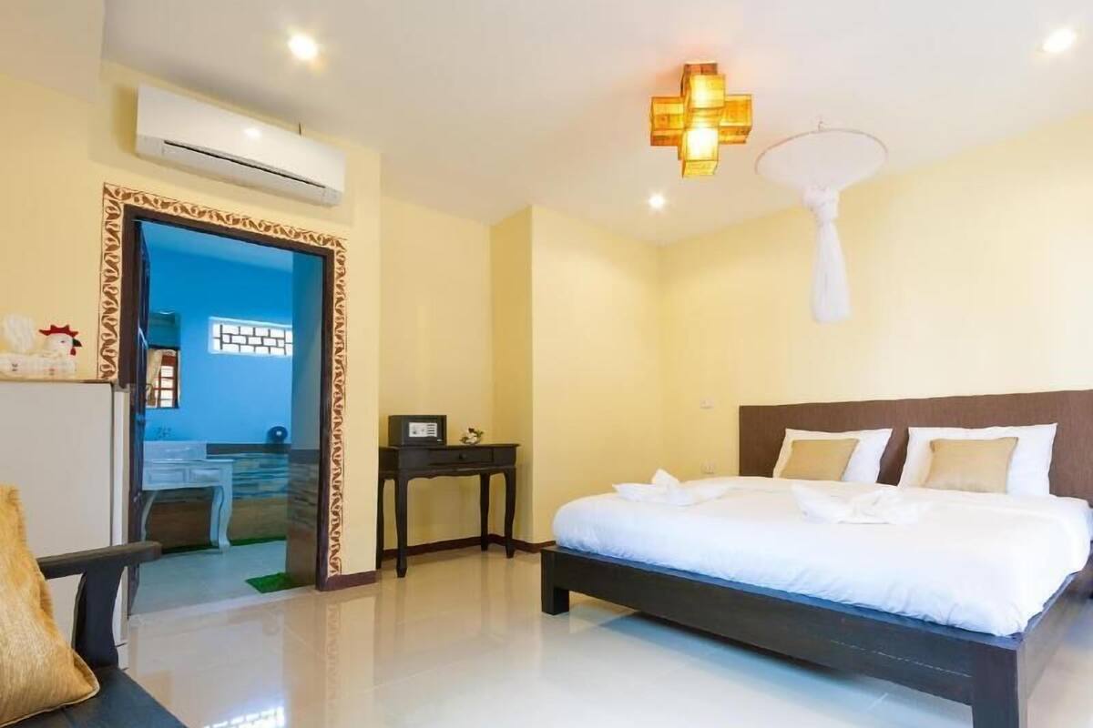 A hotel room with a bed, bedside table, and a small desk with a chair.