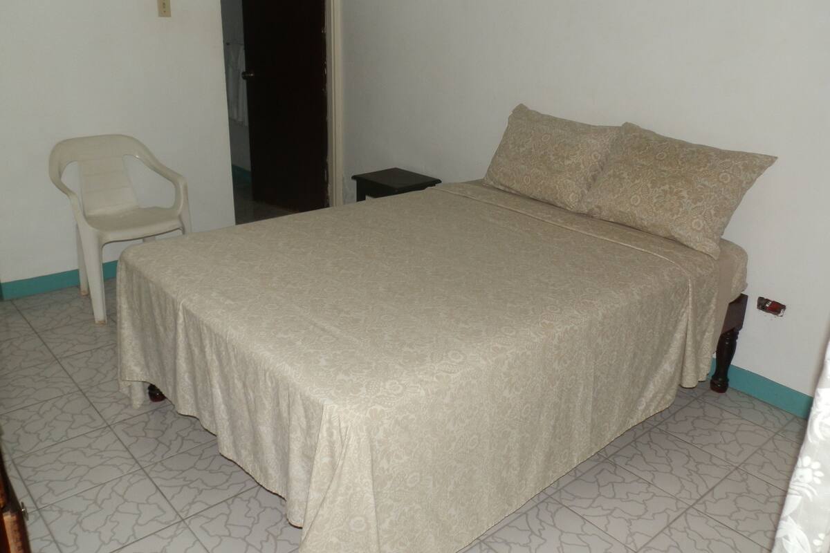 A bedroom with a bed, a chair, and a door.