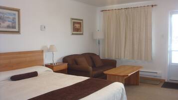 Una habitación de hotel con una cama, un sofá, una mesita, una lámpara y una ventana con cortinas.