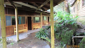 A wooden structure with a covered porch and stone pathway. - Hotel Villa Verde (Monteverde)