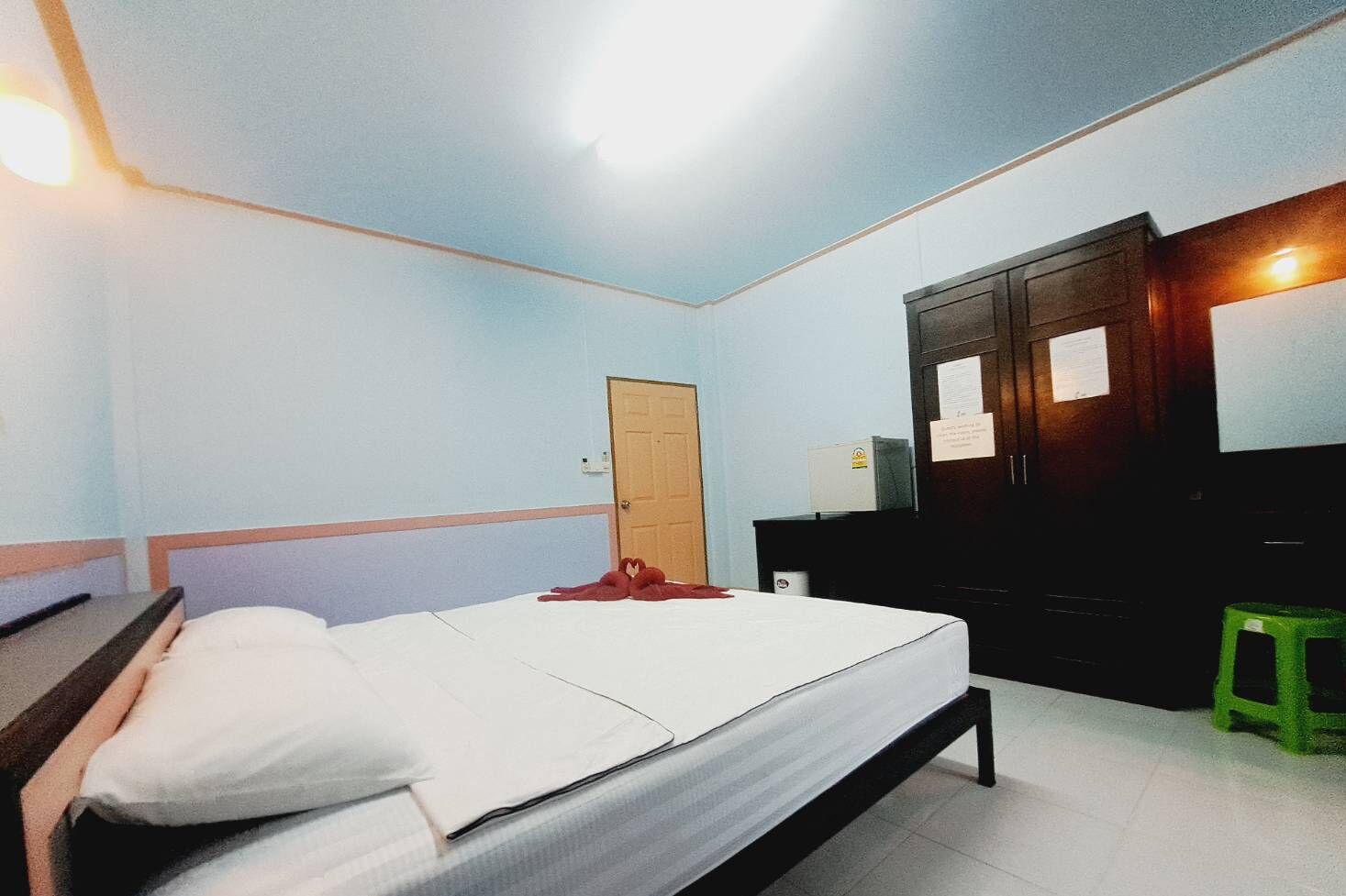 A bedroom with a bed, a desk, a wardrobe, and a stool.