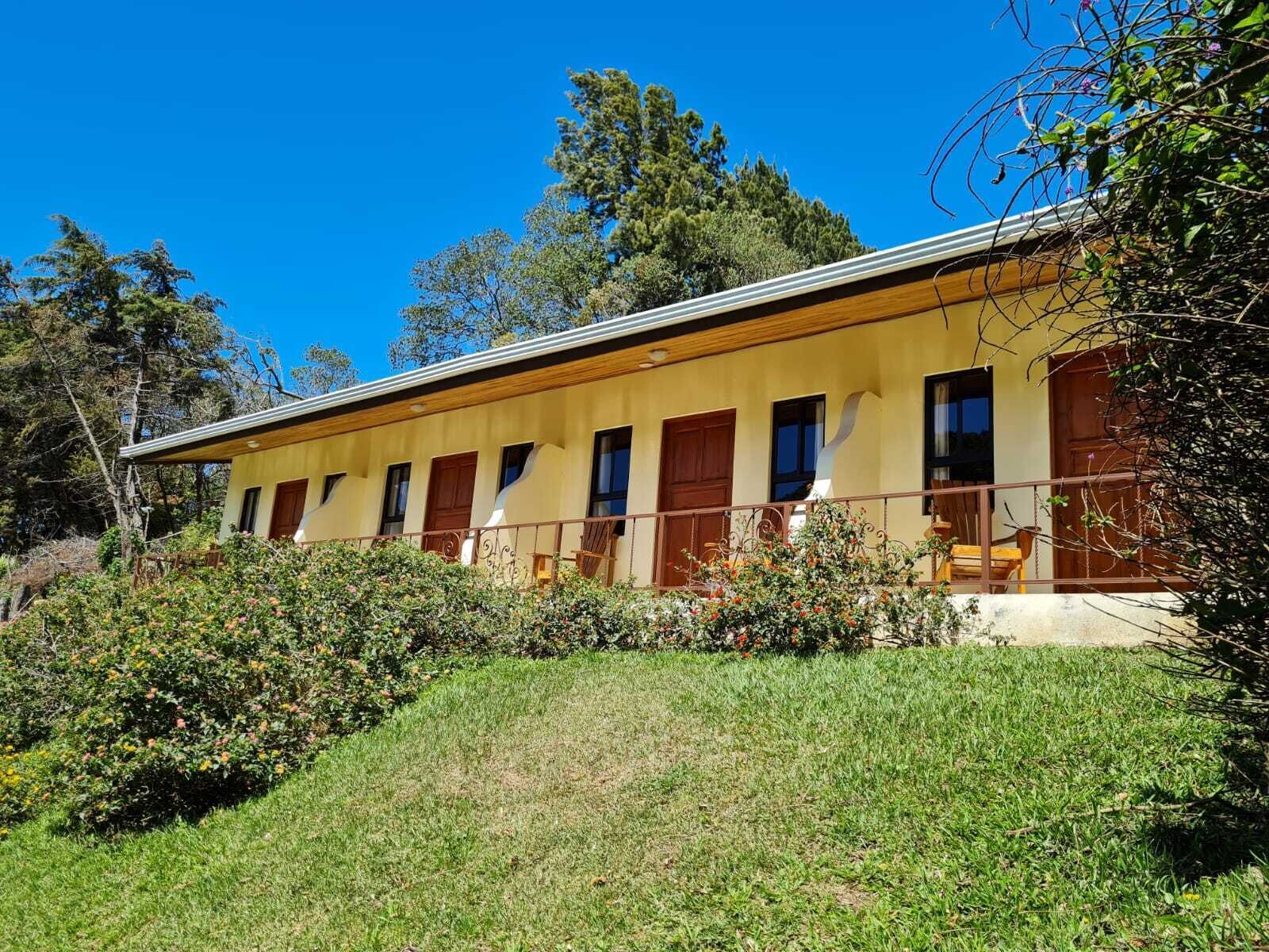A two-story building with a flat roof, a balcony with a railing, and a series of windows.