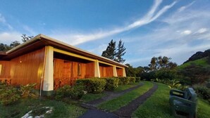 Un edificio de madera con un sendero que lo lleva a él, rodeado de vegetación y árboles.