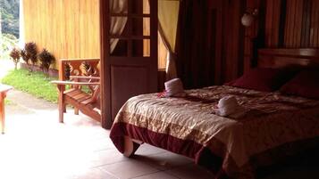 Una habitación de madera con una cama, un banco y vistas al verdor exterior.