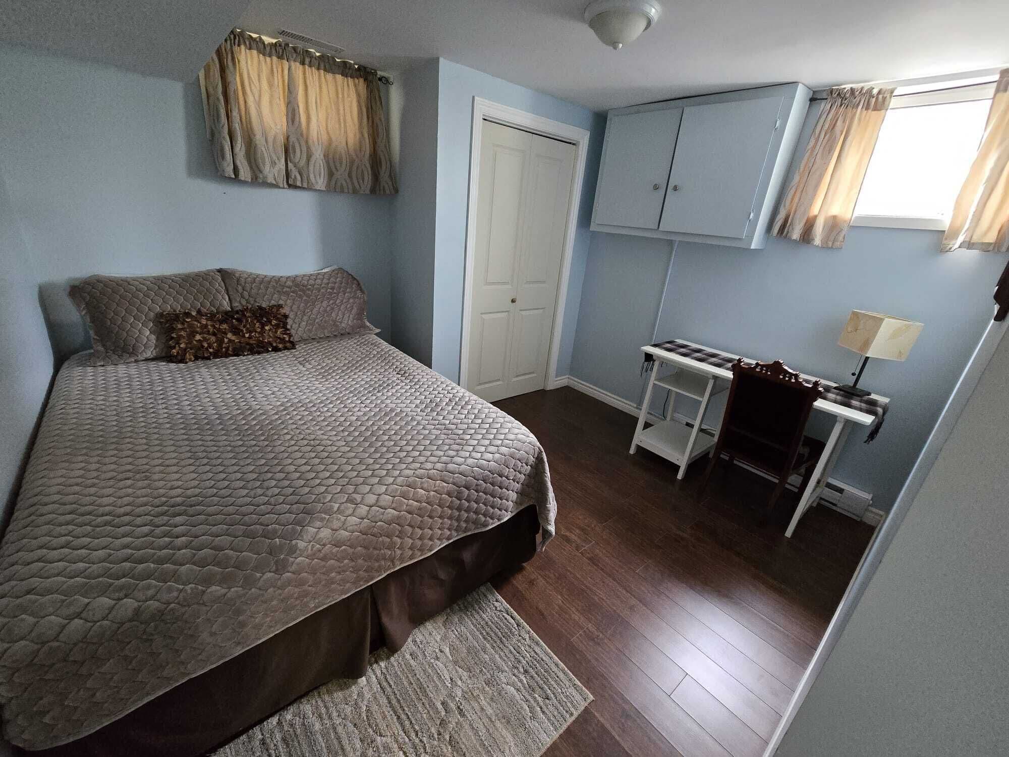 Un dormitorio con cama, escritorio, silla, lámpara y armario.