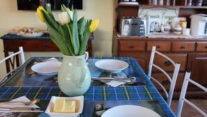 A dining table with a plaid tablecloth, a vase with flowers, and a plate of butter. - Antigonish Evergreen Inn (Sylvan Valley)
