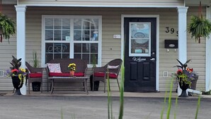 The exterior of the Antigonish Evergreen Inn, featuring a welcoming entrance with a black door, a bench outside, and potted plants. - Antigonish Evergreen Inn (Sylvan Valley)