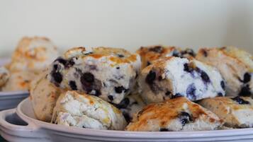Une assiette en céramique blanche sur laquelle on voit plusieurs muffins aux myrtilles.