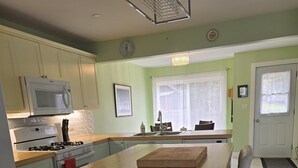 A compact kitchen with a central island, a microwave, stove, and a sink. - Antigonish Evergreen Inn (Sylvan Valley)