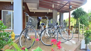 A covered outdoor area with bicycles parked under a shelter, surrounded by potted plants and a fire hydrant. - Lanta Nice Beach House (Ko Lanta)