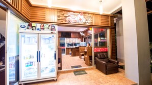 A restaurant with a 'Welcome' mat, a refrigerator stocked with beverages, and a seating area with a brown leather chair. - Lanta Nice Beach House (Ko Lanta)