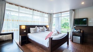 A hotel room with a large bed, a TV, a desk, and a view of greenery outside. - Lanta Nice Beach House (Ko Lanta)