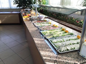 A buffet setup with various food items and utensils.