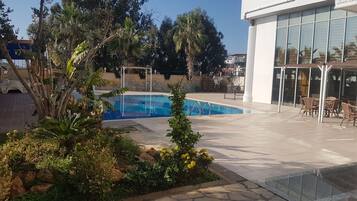 Una piscina al aire libre, sillones reclinables de piscina