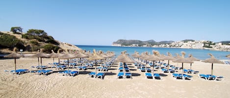 Nära stranden, vit sandstrand, solstolar och parasoller