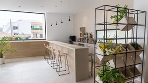 A modern kitchen with a bar area, large windows, and a plant shelf. - Aparthotel Novo Mar (Calvia)