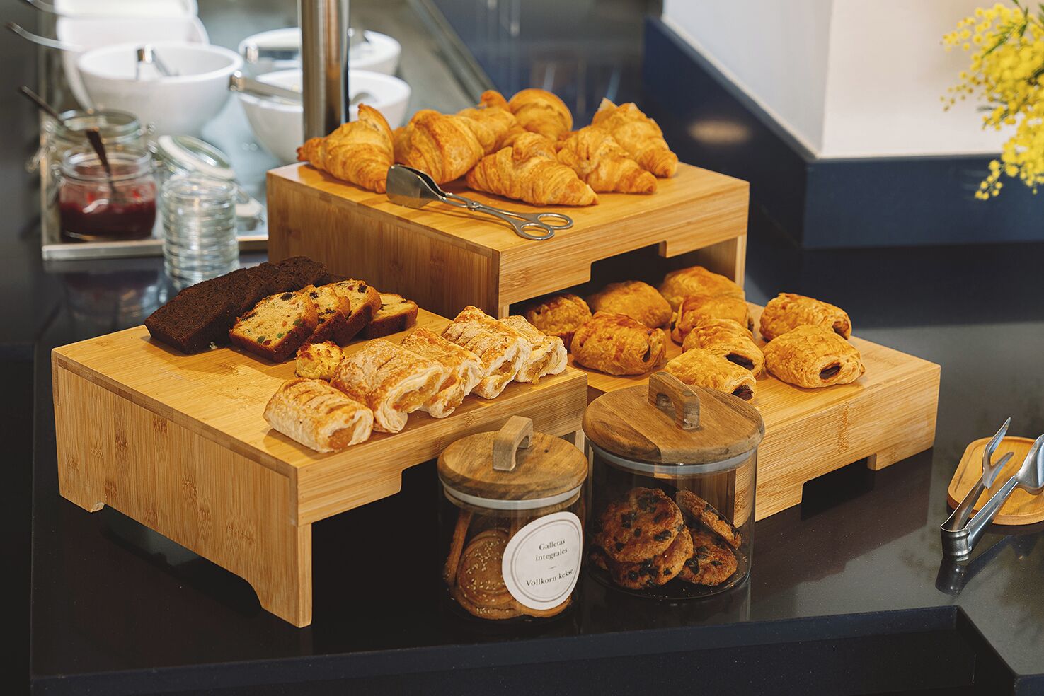 Un buffet proposant une variété de produits de boulangerie, notamment des croissants, du pain et des pâtisseries, présentés sur des planches en bois.