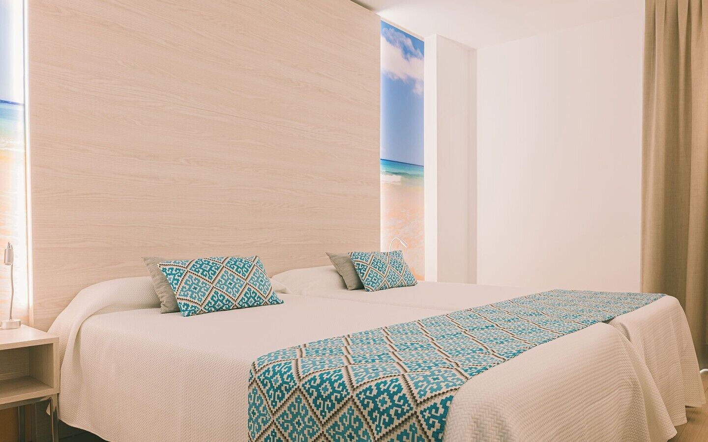 Habitación de hotel con cama, almohadas, mesita de noche y un cuadro en la pared.