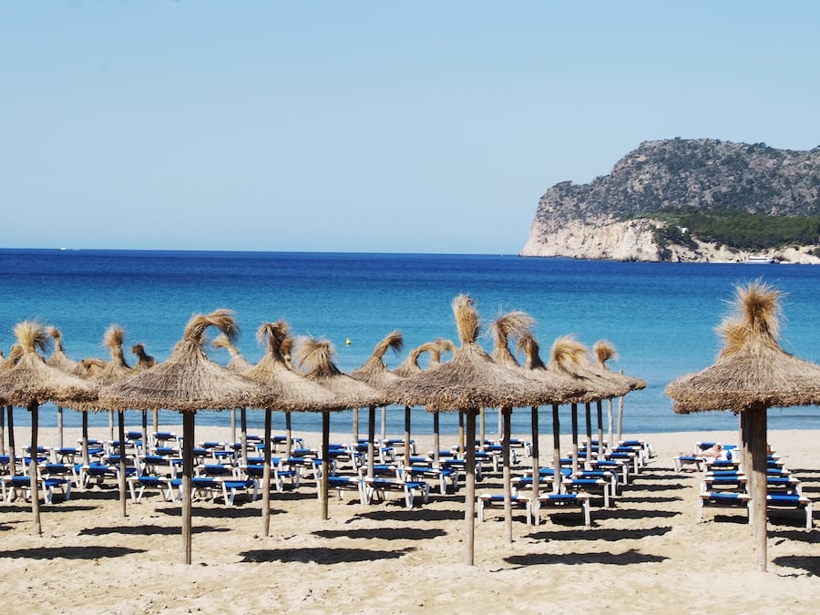 In Strandnähe, weißer Sandstrand, Liegestühle, Sonnenschirme
