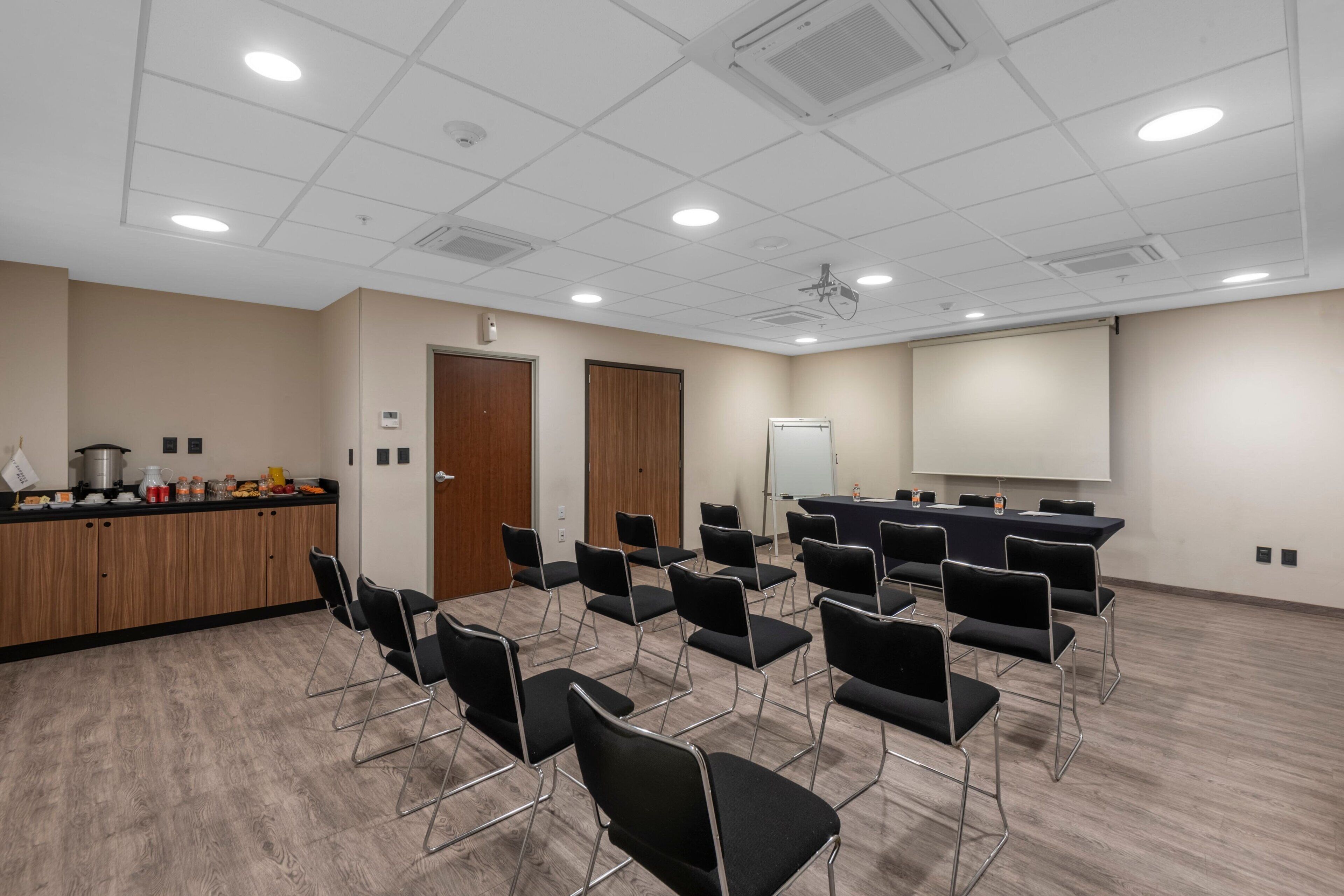 A conference room with a whiteboard, projector, and a long table with chairs.