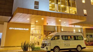 A modern hotel building with a white van parked in front, labeled 'CITY EXPRESS PLUS BY MARRIOTT.' - City Express Plus by Marriott Guadalajara Palomar (Tlajomulco de Zúñiga)