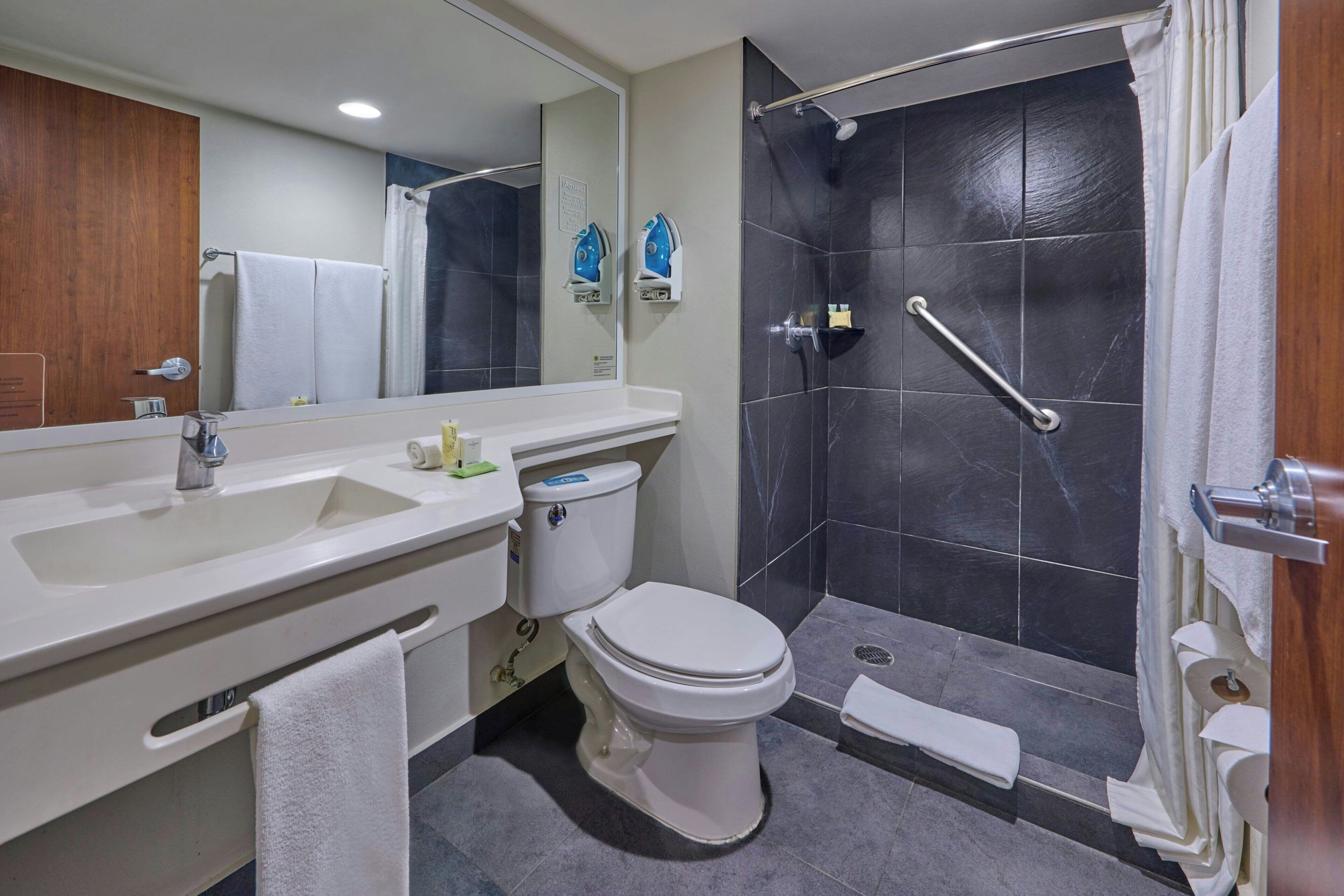 Une salle de bain moderne équipée d’un lavabo, de toilettes et d’une douche.
