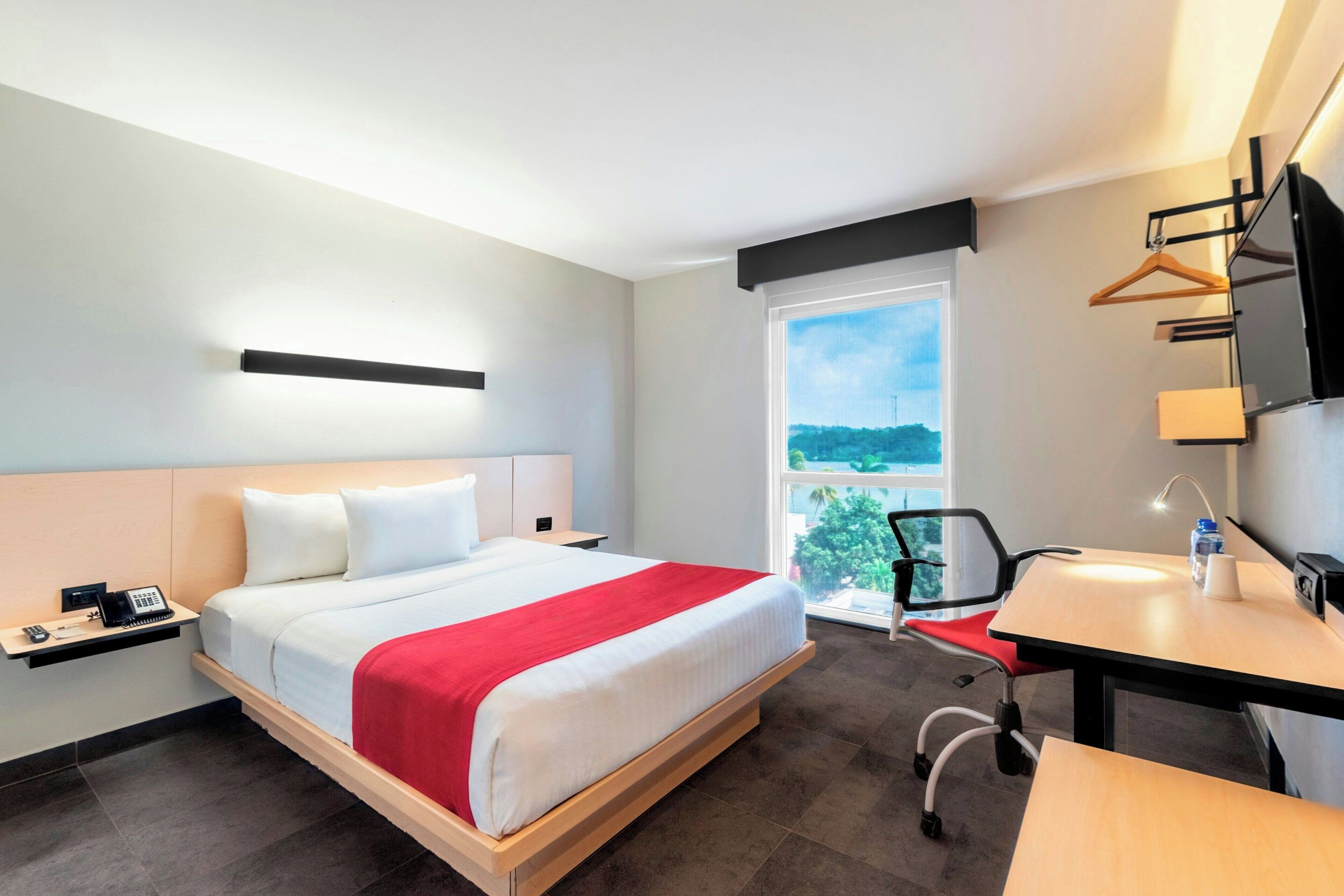 Een hotelkamer met een bed, bureau, stoel en een raam met uitzicht.