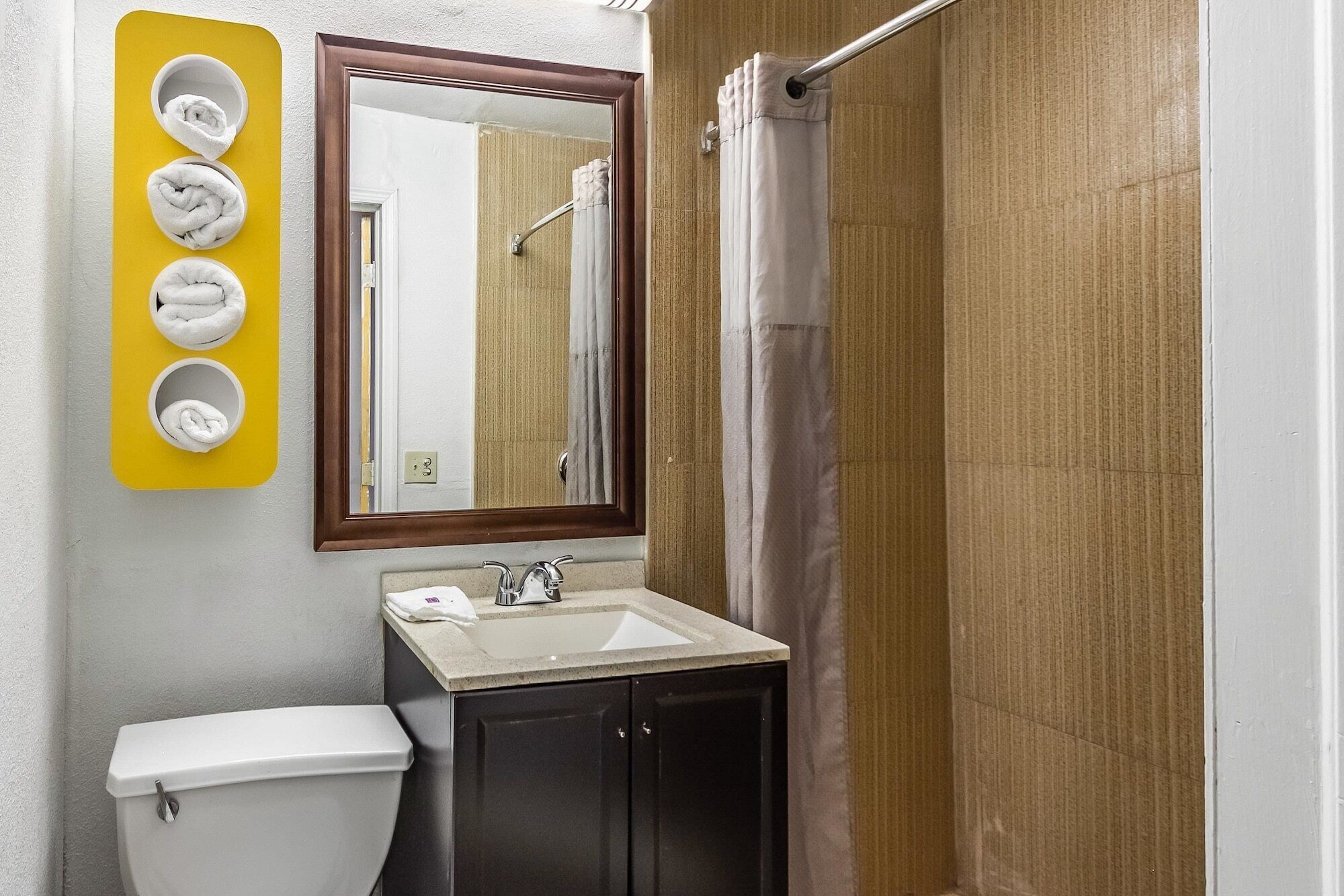 Une salle de bain avec des toilettes, un lavabo et un miroir. Il y a quatre porte-serviettes au mur.