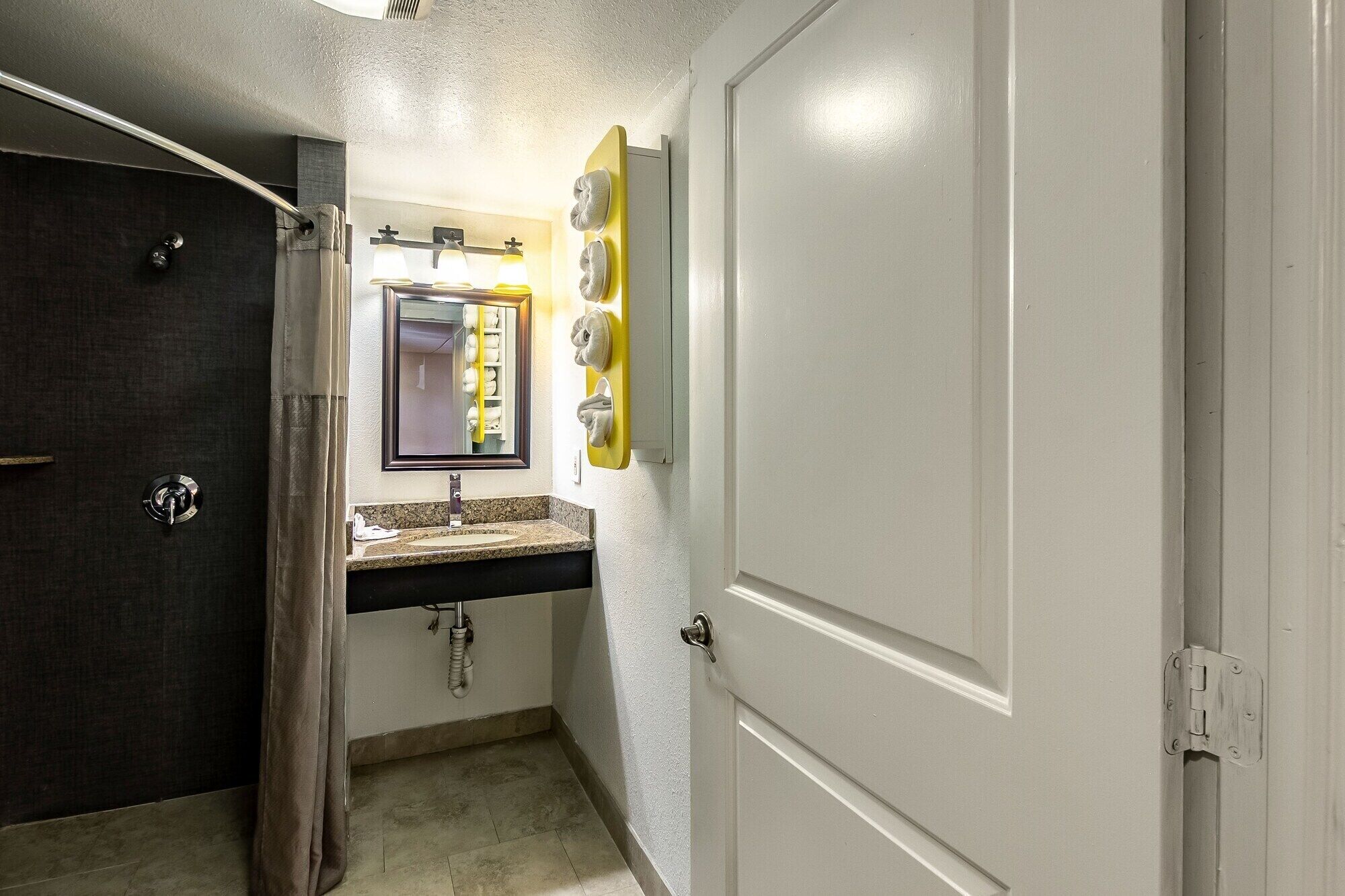 A bathroom with a dark door, a sink with a mirror, and a towel rack.