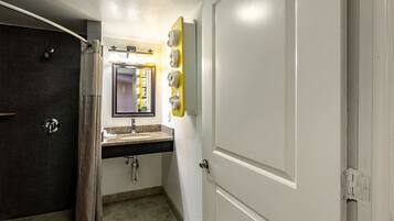 A bathroom with a dark door, a sink with a mirror, and a towel rack.