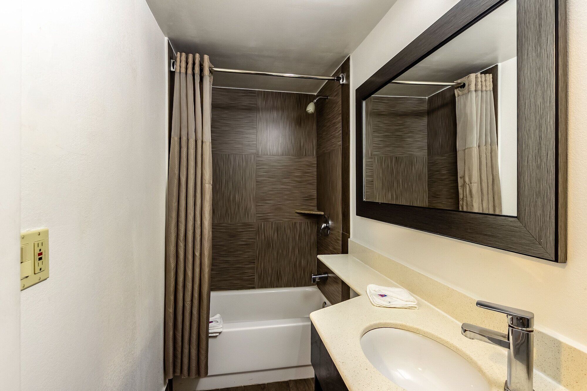 A bathroom with a bathtub, a sink, and a mirror.