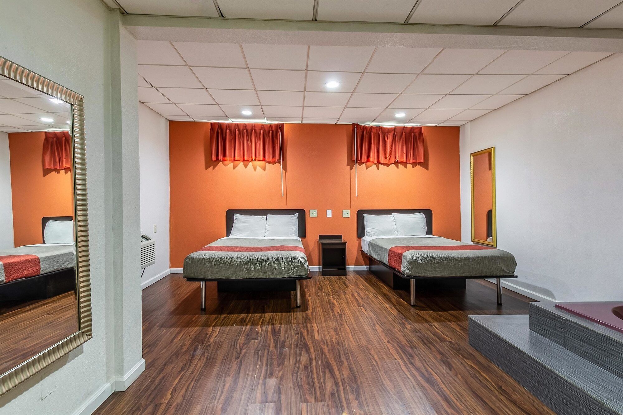 A hotel room with two beds, a mirror, and a small table.