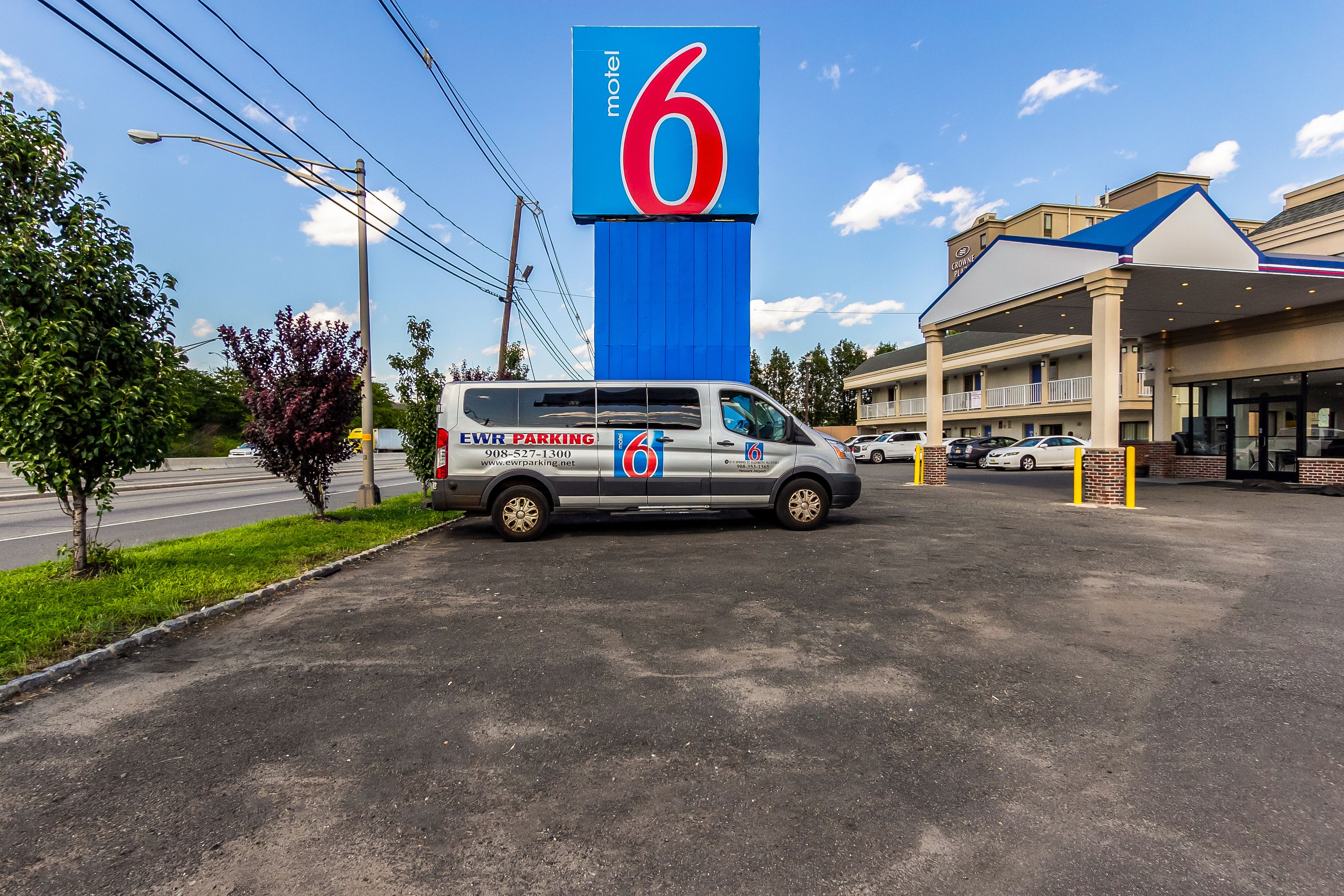 Een motel met een opvallend bord met het cijfer '6', een parkeerplaats en een gebouw met een blauw dak.