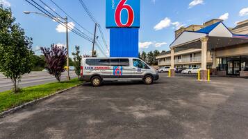 Een motel met een opvallend bord met het cijfer '6', een parkeerplaats en een gebouw met een blauw dak.