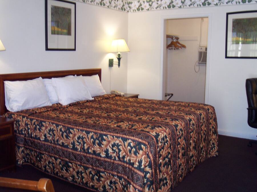 A neatly made bed with a patterned bedspread, a bedside lamp, and a framed picture on the wall.