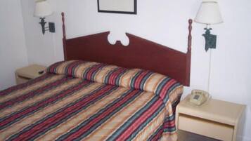 A single bed with a striped bedspread, two bedside tables with lamps, and a framed picture on the wall.