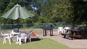 An outdoor patio area with a table and chairs, a barbecue grill, and a picnic table. - Shore Hills Motel (Manasquan)