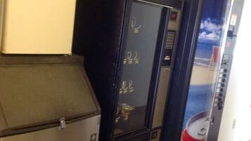 A row of vending machines and a refrigerator in a hallway.