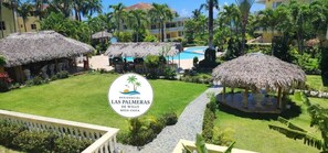 A resort with thatched-roof structures, a swimming pool, and lush greenery.