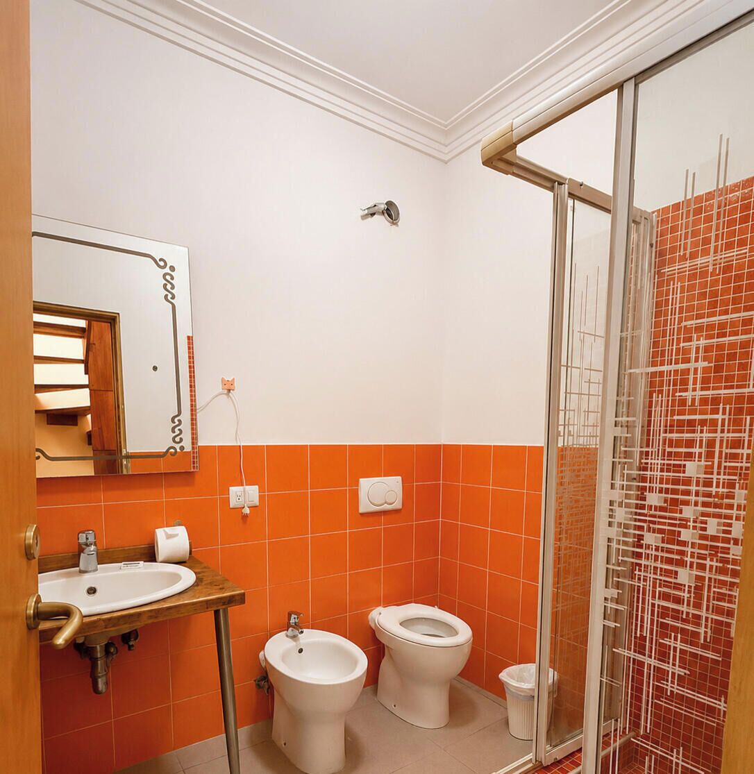 A bathroom with a sink, bidet, toilet, and a glass shower enclosure.