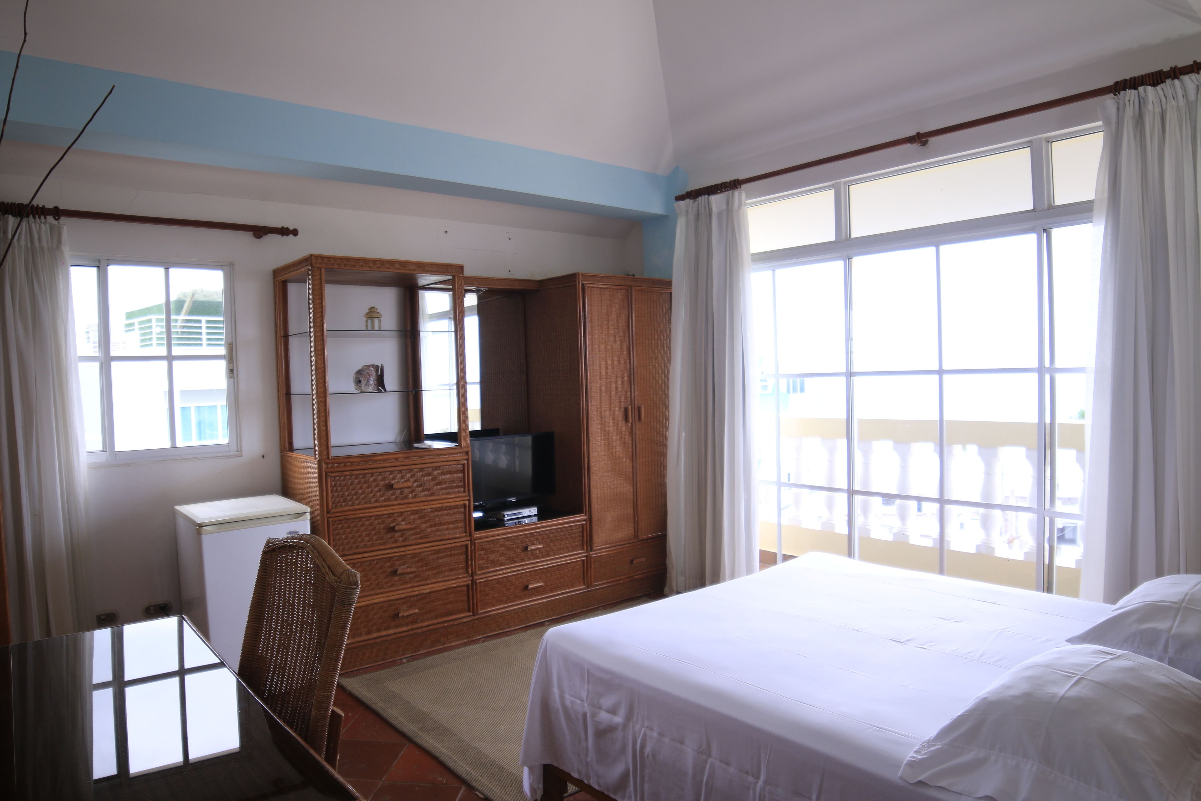 A hotel room with a bed, a desk, a television, and a wardrobe.