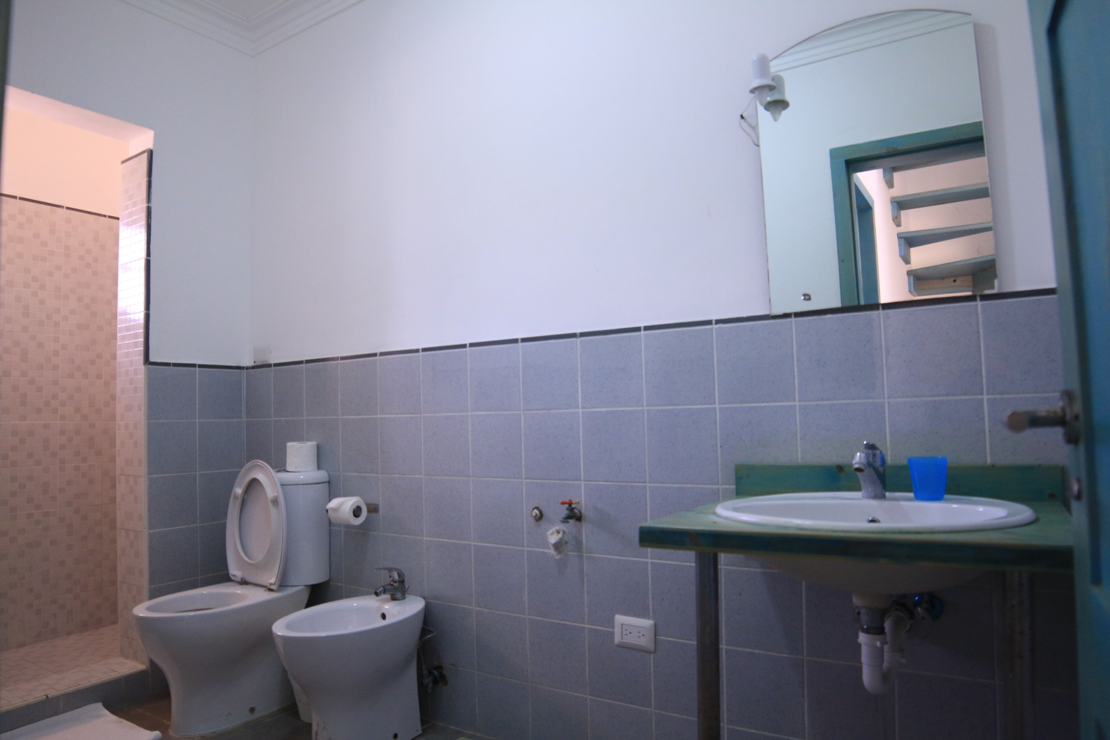 A bathroom with two toilets, a sink, and a mirror.