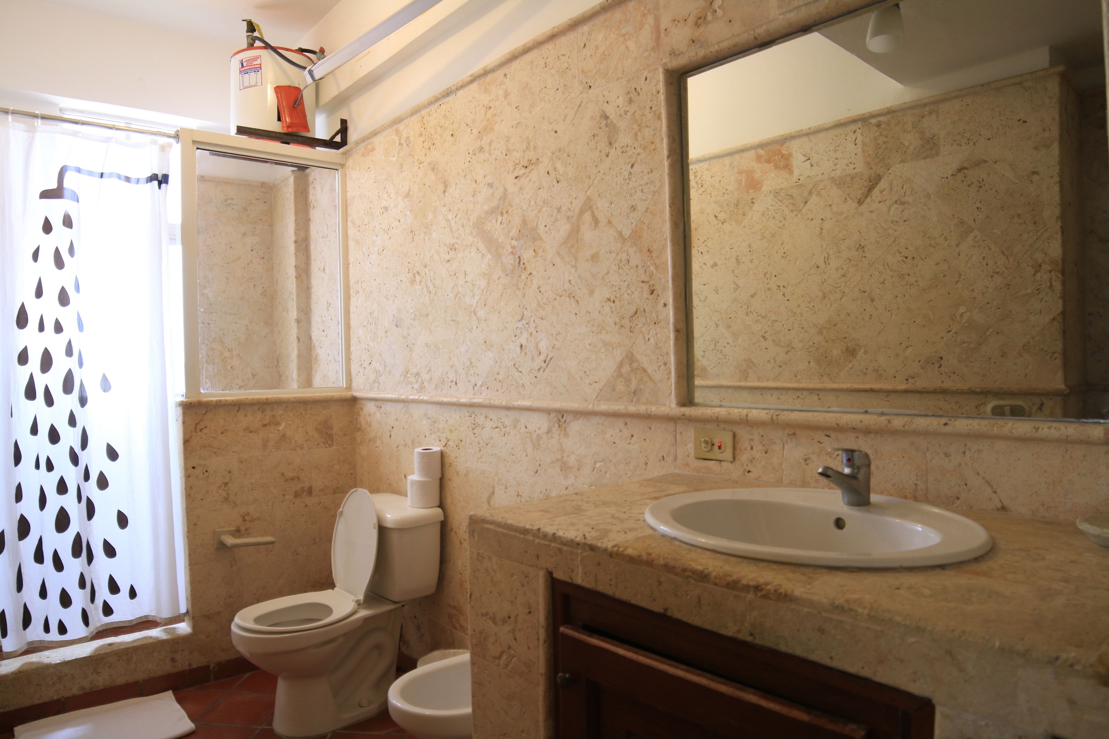 A bathroom with a toilet, bidet, sink, and mirror.