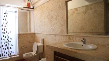 A bathroom with a toilet, bidet, sink, and mirror.