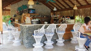 Ein überdachter Außenbereich mit weißen Korbstühlen und einer Steintheke.