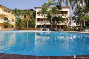 A swimming pool with lounge chairs and palm trees.