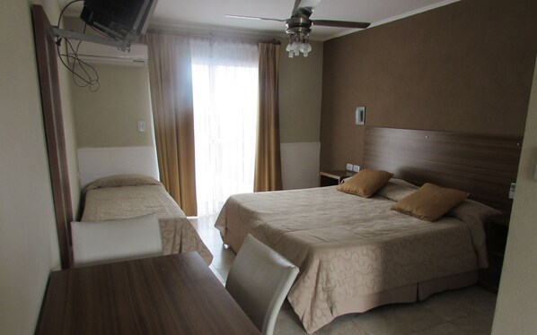 Habitación de hotel con dos camas, un escritorio y un ventilador de techo.