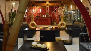 Un espace d’accueil doté d’un plafond en bois, d’un comptoir de réception, de deux vases ornés de branches et d’une table décorée de bougies.