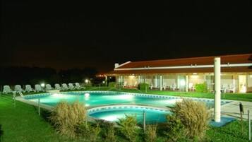 Area piscina con sedie a sdraio e un edificio con tetto rosso.